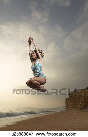 Stock Photo - Woman jumping with beach background.. Fotosearch