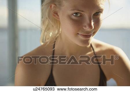 Stock Image - Young woman by windows of beach house.. Fotosearch