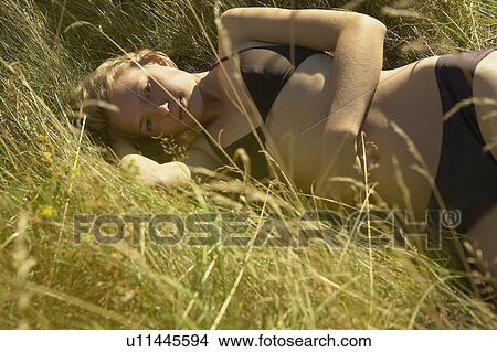 Young Woman lying in grass. View Large Photo Image Picture - Young Woman lying in grass.. Fotosearch