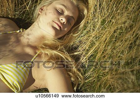 Stock Photo - Young woman lying in long grass.. Fotosearch