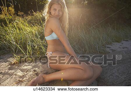 Picture - Young Woman Sitting at edge of beach.. Fotosearch