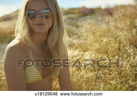 Stock Photo - Young Woman Sitting in Long grass.. Fotosearch