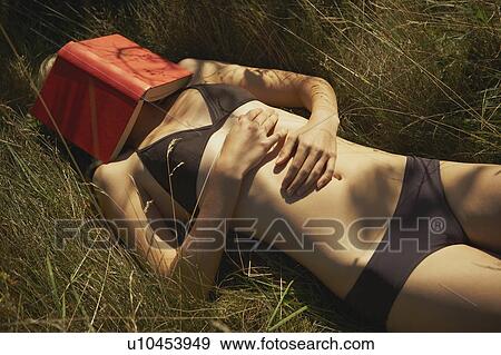 Stock Photo - Young woman with book covering face.. Fotosearch