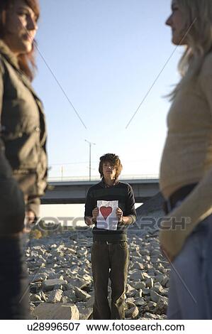 Boy holding paper heart looking at girl View Large Photo Image Stock Photo - Boy holding paper heart looking at girl. Fotosearch