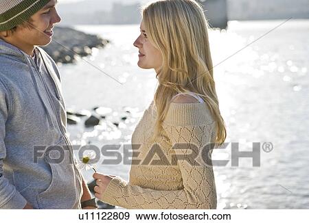 Stock Photo - Boy smiling at girl holding flower. Fotosearch