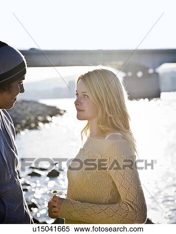 Stock Photography - Girl holding flower looking at boy. Fotosearch