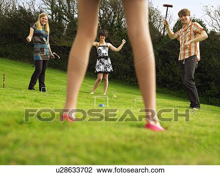 Stock Image - Man and women playing croquet in garden. Fotosearch
