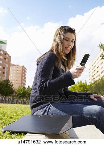 Teenage female on mobile phone in park View Large Photo Image Stock Image - Teenage female on mobile phone in park. Fotosearch