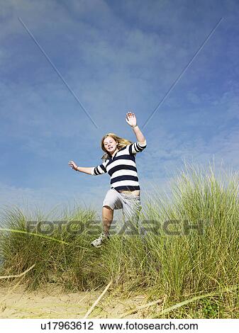 Stock Image - Teenage girl jumping through grass . Fotosearch