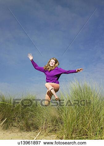 Teenage girl jumping through grass View Large Photo Image Stock Photo - Teenage girl jumping through grass. Fotosearch