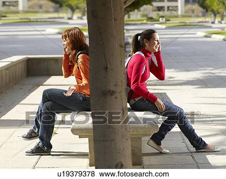 Two teenagers on their mobile phone View Large Photo Image Stock Photo - Two teenagers on their mobile phone. Fotosearch