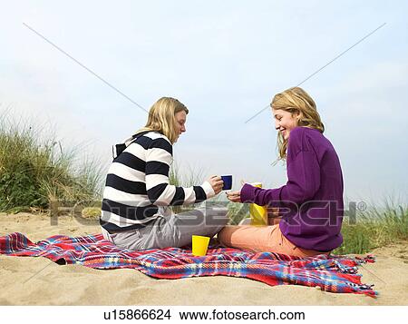 Picture - Women drinking hot drink, on blanket. Fotosearch