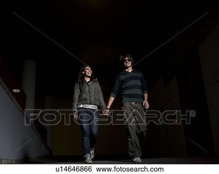 Stock Photograph - Young couple holding hands in underpass. Fotosearch