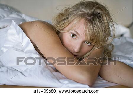 Stock Image - Young woman wrapped in a duvet. Fotosearch