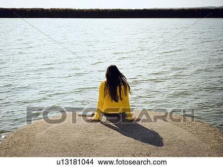 Picture - Girl sitting by lake.. Fotosearch