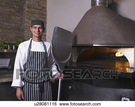 Pizza chef holding paddle in front of oven View Large Photo Image Stock Photograph - Pizza chef holding paddle in front of oven. Fotosearch