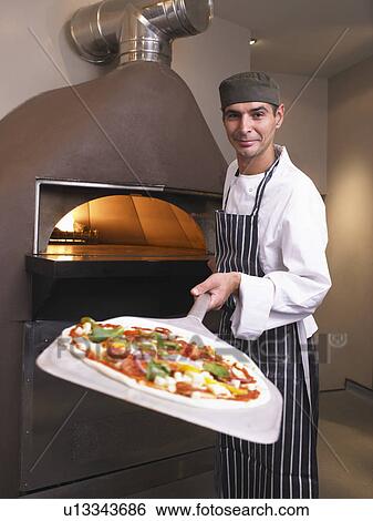 Pizza chef holding pizza in front of oven View Large Photo Image Stock Photograph - Pizza chef holding pizza in front of oven. Fotosearch