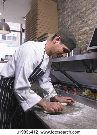 Stock Image - Pizza chef rolling pizza dough. Fotosearch
