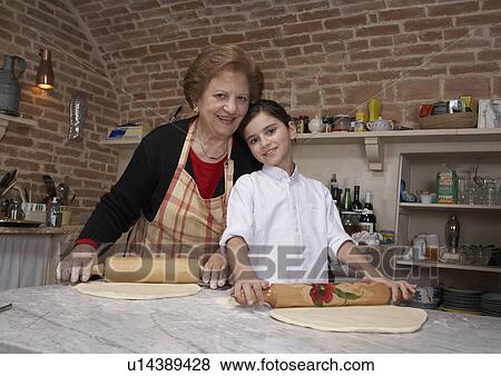 Stock Photo - Senior woman and granddaughter (9-11) rolling pastry, portrait. Fotosearch