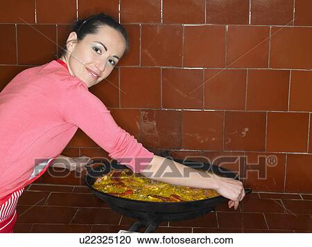 Young woman lifting large paella pan from stove, smiling View Large Photo Image Stock Image - Young woman lifting large paella pan from stove, smiling. Fotosearch