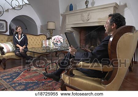Stock Photography - Businessman using laptop sitting in living room. Fotosearch