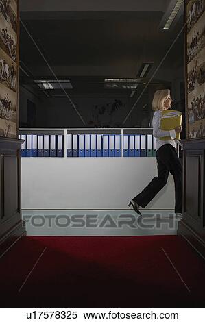 Stock Photography - Businesswoman in a hallway with binders . Fotosearch