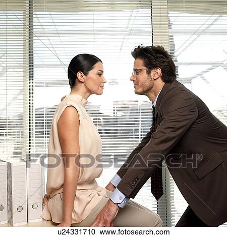 Stock Image - Couple facing each other in office. Fotosearch