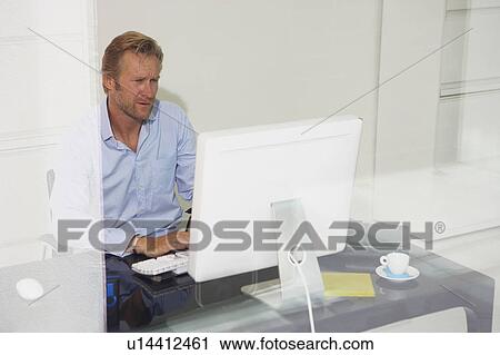 Stock Image - Man at computer with reflections.. Fotosearch
