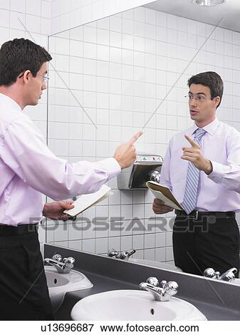 Man practicing speech in office washroom mirror View Large Photo Image Stock Photo - Man practicing speech in office washroom mirror. Fotosearch