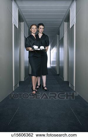 Stock Image - Two women with coffee cups in a hallway. Fotosearch