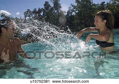 Couple playing with water in the swimming pool View Large Photo Image Stock Image - Couple playing with water in the swimming pool. Fotosearch