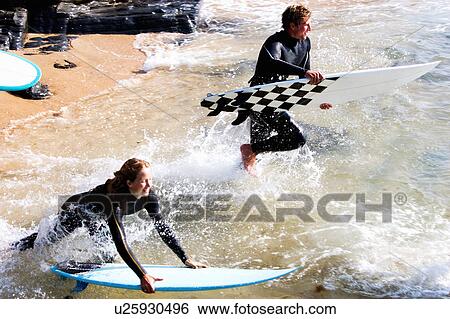 Couple with surfboards splashing in the water smiling. View Large Photo Image Stock Photograph - Couple with surfboards splashing in the water smiling.. Fotosearch