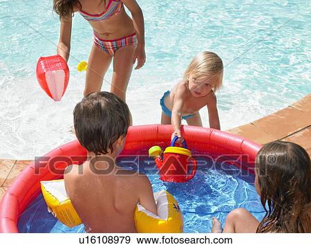 Four children playing in a kiddie pool near a backyard pool. View Large Photo Image Stock Photo - Four children playing in a kiddie pool near a backyard pool.. Fotosearch