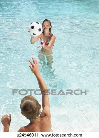 Stock Image - Kids playing with a ball in pool.. Fotosearch
