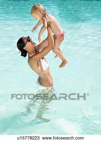 Stock Image - Woman and young boy playing in a pool smiling.. Fotosearch