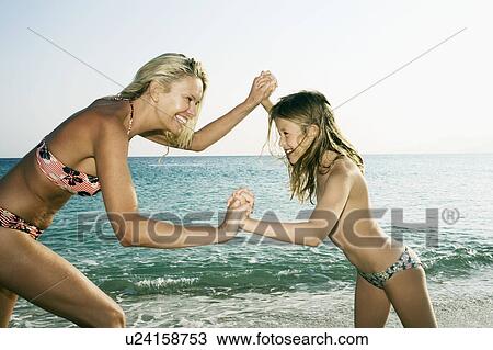 Stock Image - Woman and young girl being playful at the beach smiling.. Fotosearch