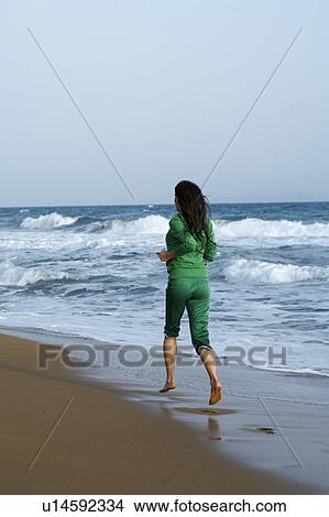 Woman jogging away from camera while on beach. View Large Photo Image Picture - Woman jogging away from camera while on beach.. Fotosearch
