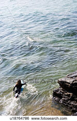 Stock Photograph - Woman lying on surfboard in the water.. Fotosearch