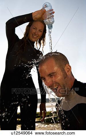 Woman pouring water over laughing man's head. View Large Photo Image Picture - Woman pouring water over laughing man's head.. Fotosearch