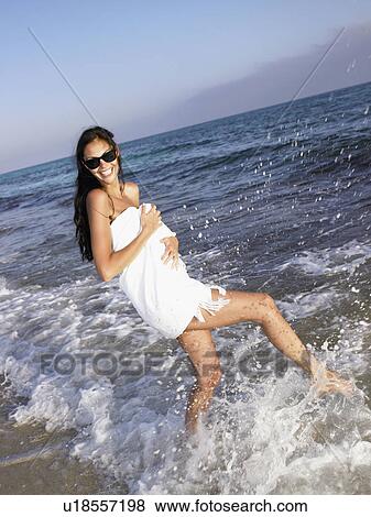 Woman splashing in water wearing a towel at the beach smiling. View Large Photo Image Stock Photo - Woman splashing in water wearing a towel at the beach smiling.. Fotosearch