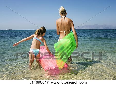 Woman with young girl at the beach with inflatable rafts. View Large Photo Image Stock Photo - Woman with young girl at the beach with inflatable rafts.. Fotosearch