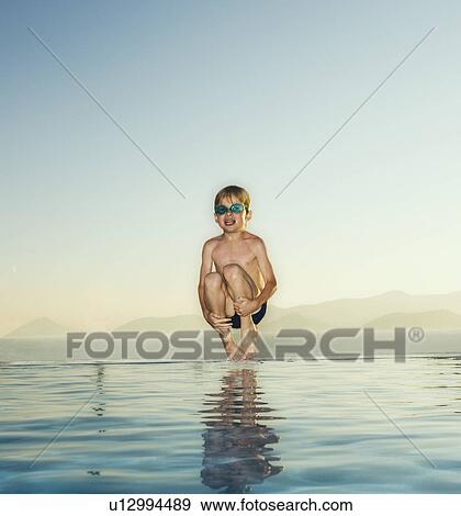 Young boy jumping into an infinity pool. View Large Photo Image Stock Photo - Young boy jumping into an infinity pool.. Fotosearch