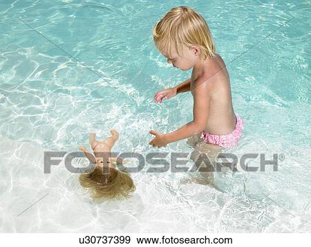 Stock Photo - Young boy playing with a doll in a pool.. Fotosearch