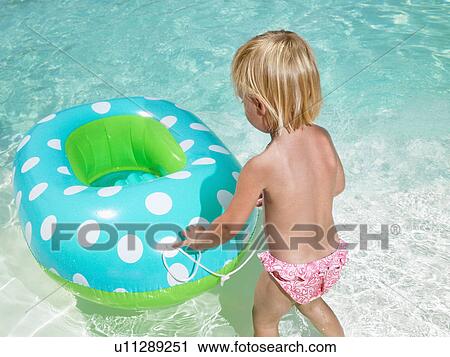 Stock Image - Young boy playing with an inner tube in a pool.. Fotosearch