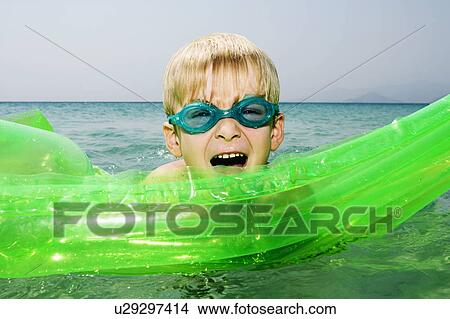 Young boy with an inflatable raft in the water with mouth open. View Large Photo Image Picture - Young boy with an inflatable raft in the water with mouth open.. Fotosearch