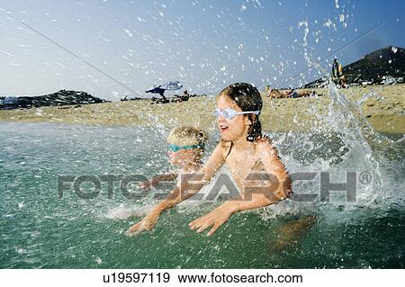 Young girl and young boy playing and splashing at the beach. View Large Photo Image Stock Photo - Young girl and young boy playing and splashing at the beach.. Fotosearch