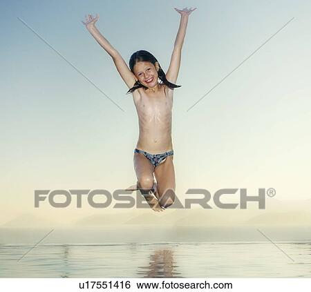 Young girl jumping into an infinity pool smiling. View Large Photo Image Stock Photograph - Young girl jumping into an infinity pool smiling.. Fotosearch