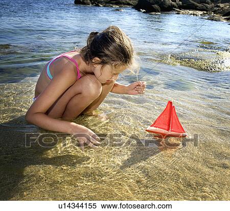 Young girl with a toy sailboat at the beach. View Large Photo Image Stock Photography - Young girl with a toy sailboat at the beach.. Fotosearch