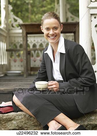 Stock Image - Businesswoman by country cottage on steps. Fotosearch