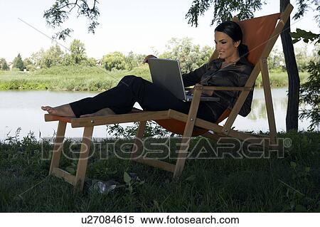 Woman on deckchair with laptop by river. View Large Photo Image Stock Photography - Woman on deckchair with laptop by river.. Fotosearch